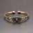 Bronze bracelet with floral design on a gray background