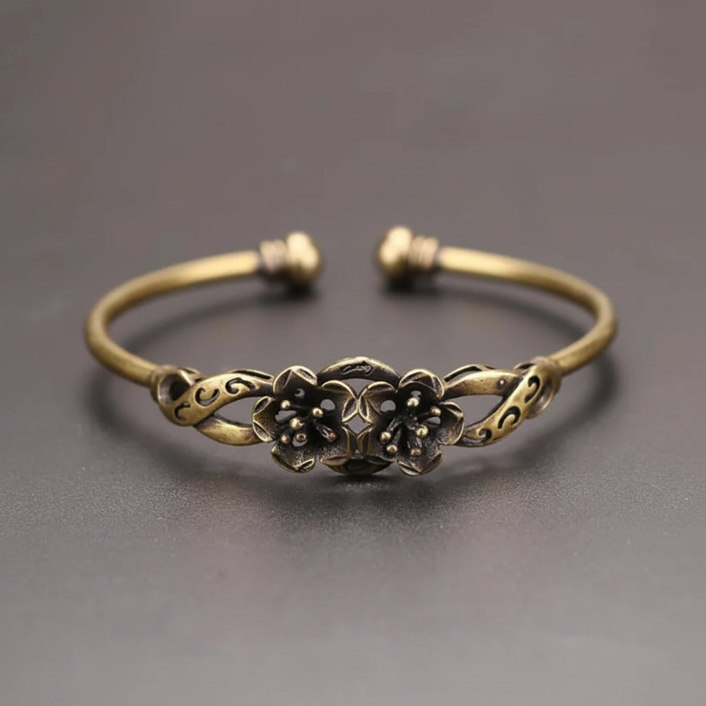 Bronze bracelet with floral design on a gray background