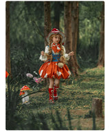A young girl in a whimsical fairy tale forest outfit, featuring a red and white polka-dot dress, red boots, and a matching hat, standing in a wooded forest path.